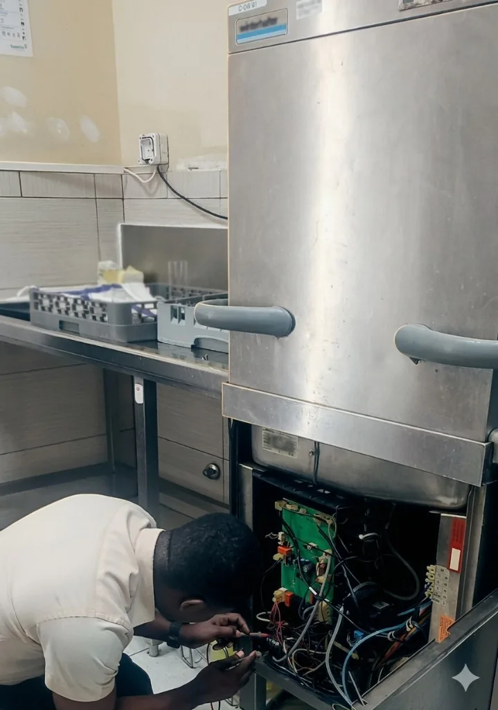 Technician servicing commercial kitchen equipment on a live hospitality site